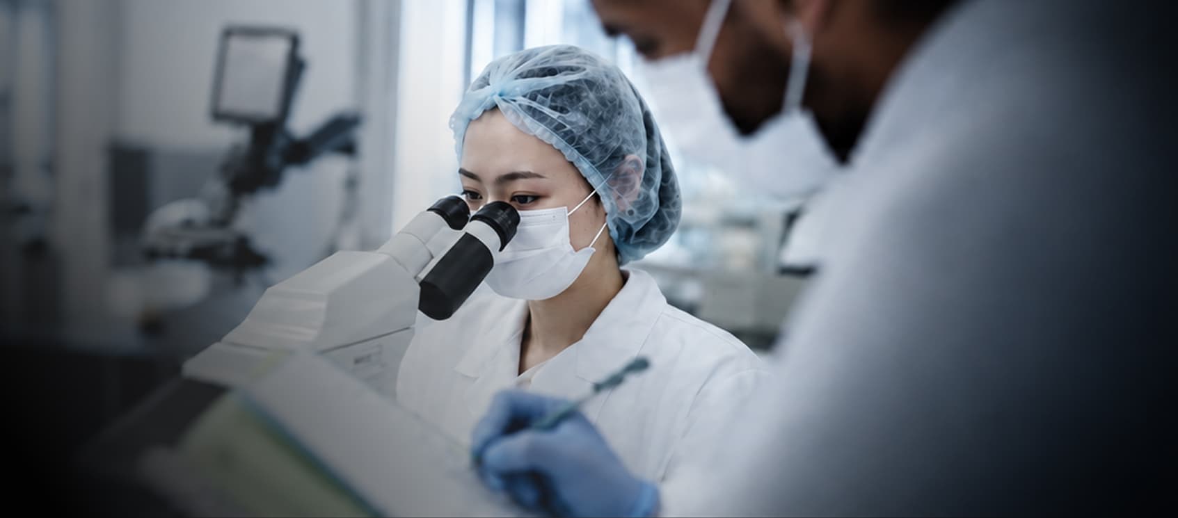 Researchers examining a sample under a microscope